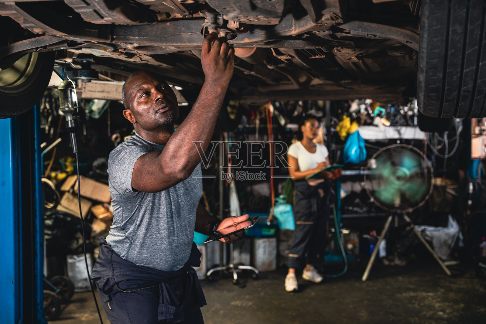 机修工正在检查汽车的悬挂装置。照片摄影图片