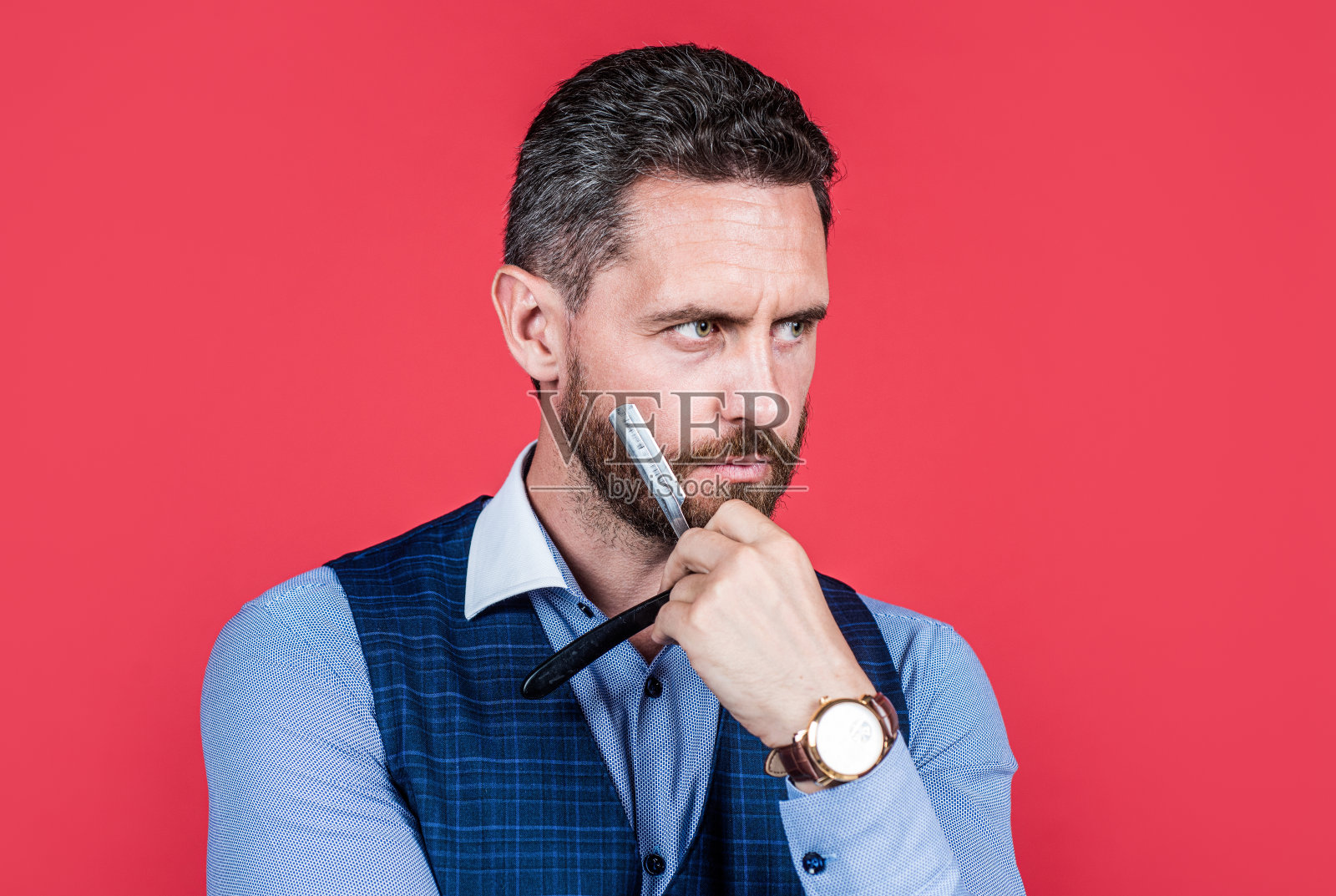 成熟严肃的男士理发师用腕表剃须用复古剃须刀片，护理头发照片摄影图片