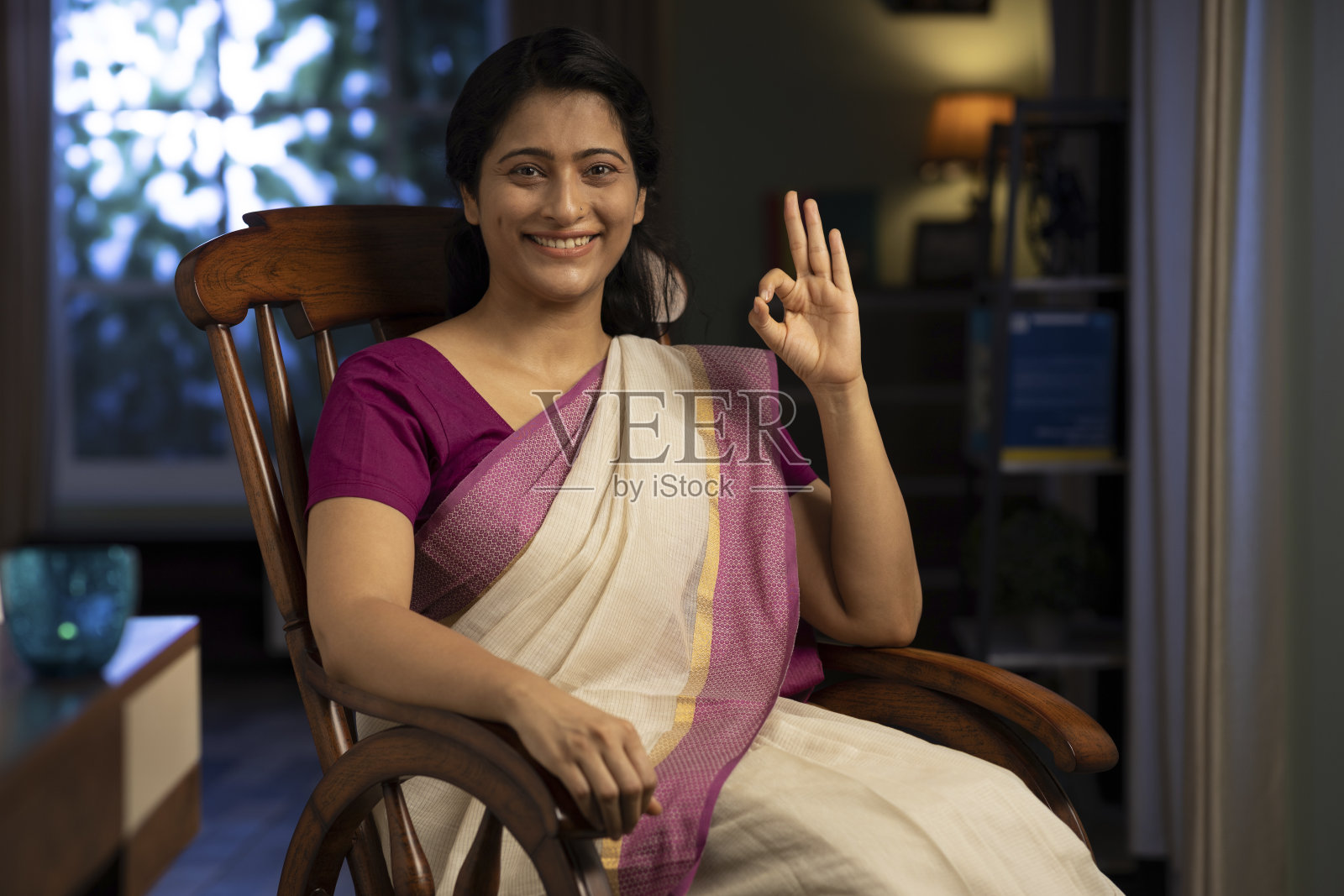 一个女人在纱丽坐在家里的摇椅上的拍摄，库存照片照片摄影图片