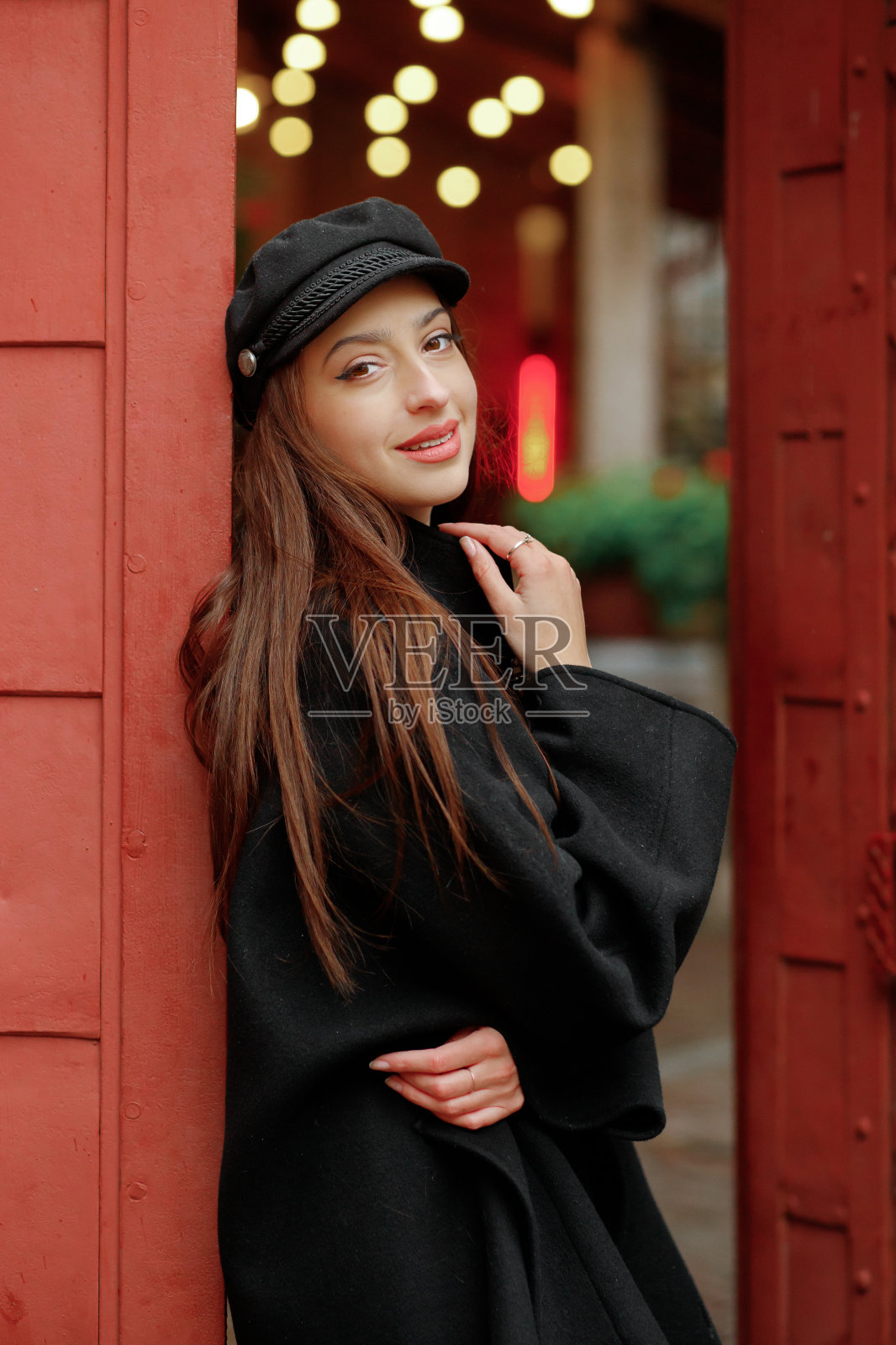 肖像快乐微笑的女孩在黑色大衣和帽子在户外摆姿势。照片摄影图片