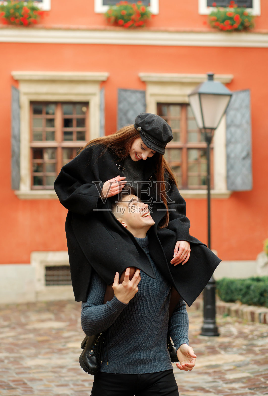 有趣的女孩坐在男孩的脖子上。快乐的夫妻照片摄影图片