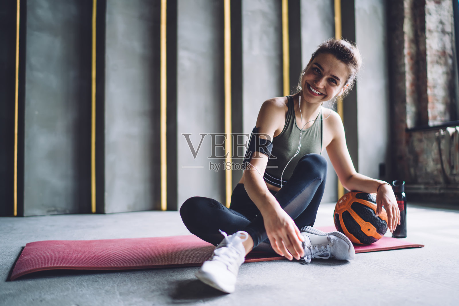 微笑的女运动员坐在垫子上的重量球照片摄影图片