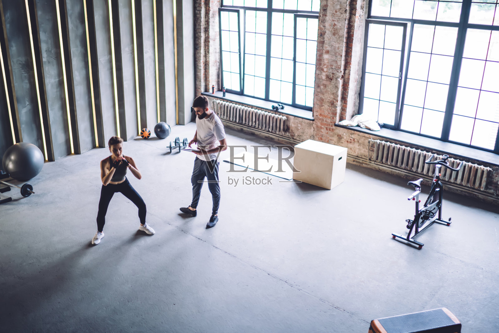 男教练在看女运动员做深蹲照片摄影图片