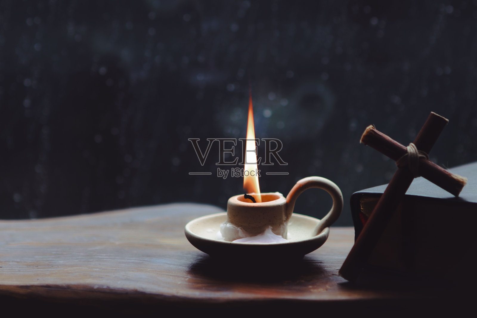 雨点和雨滴落在窗户上、蜡烛、十字架和圣经上照片摄影图片