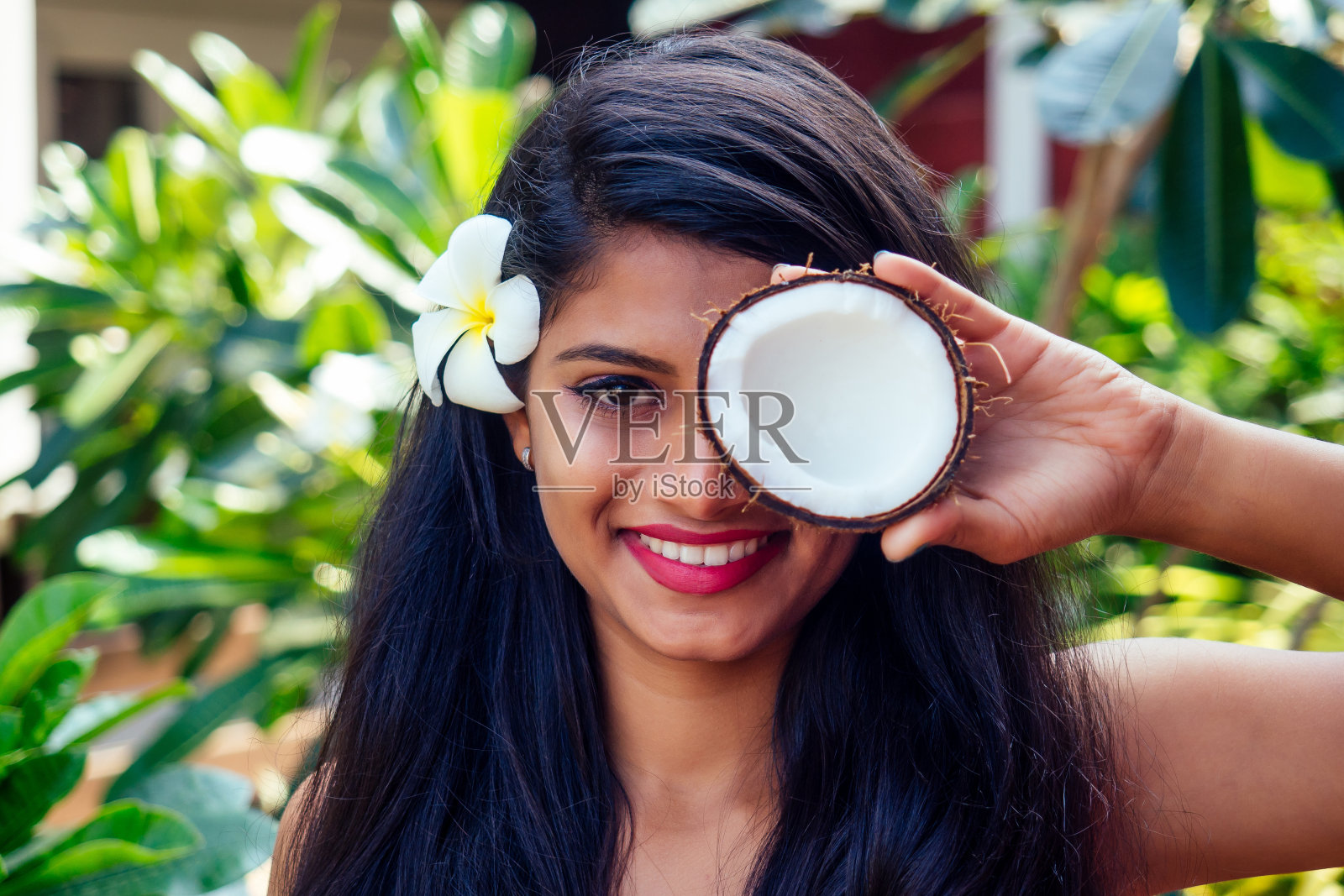 印度妇女在绿色的夏季公园自然热带应用椰子油深色头发在一只手照片摄影图片