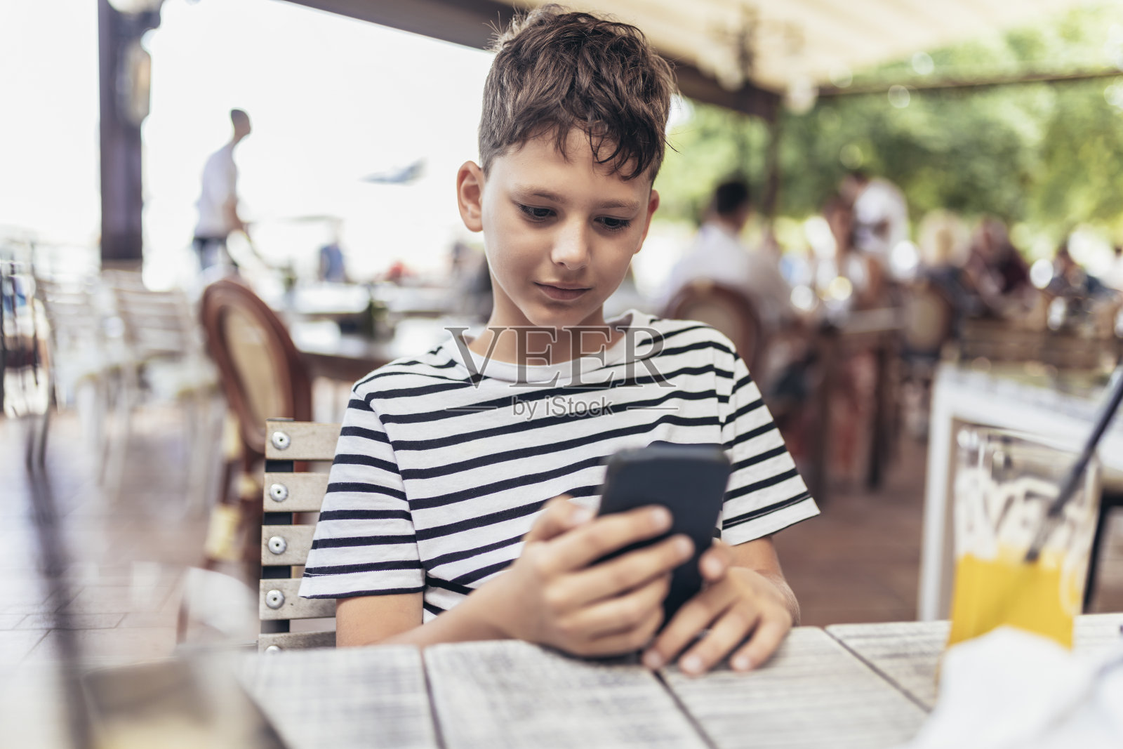 男孩沉迷于户外网络游戏。男孩使用手机和玩游戏。照片摄影图片