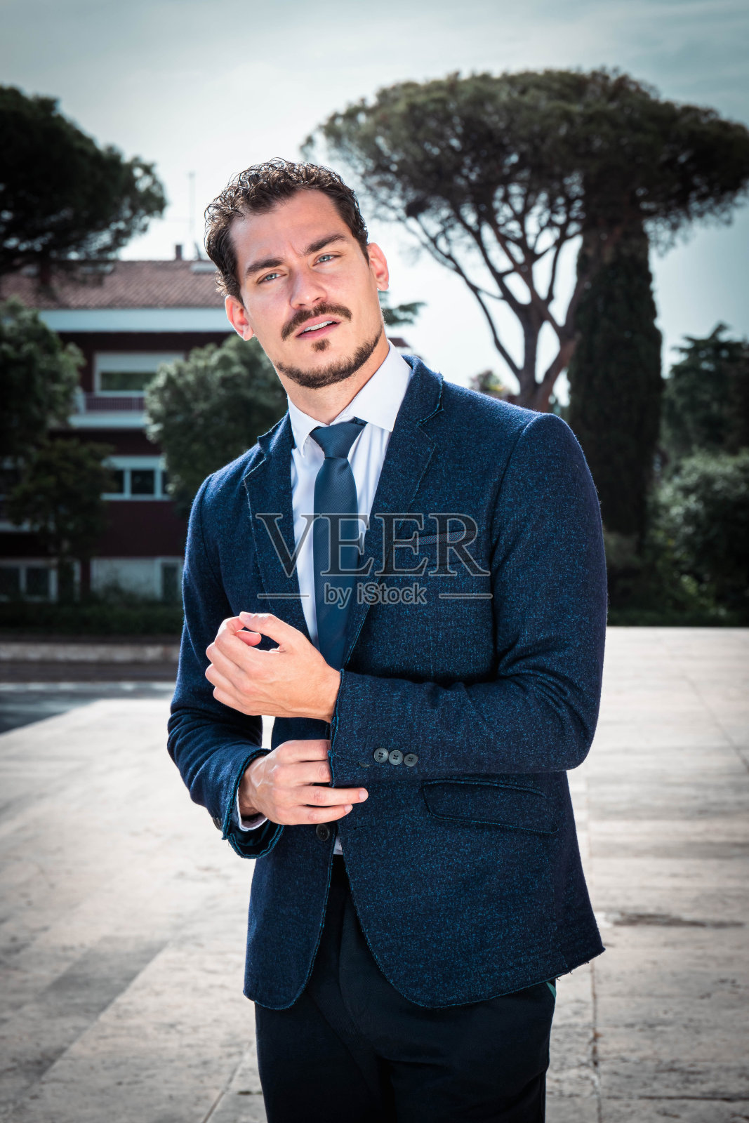 漂亮的商人在进办公室前正在整理他的夹克。照片摄影图片