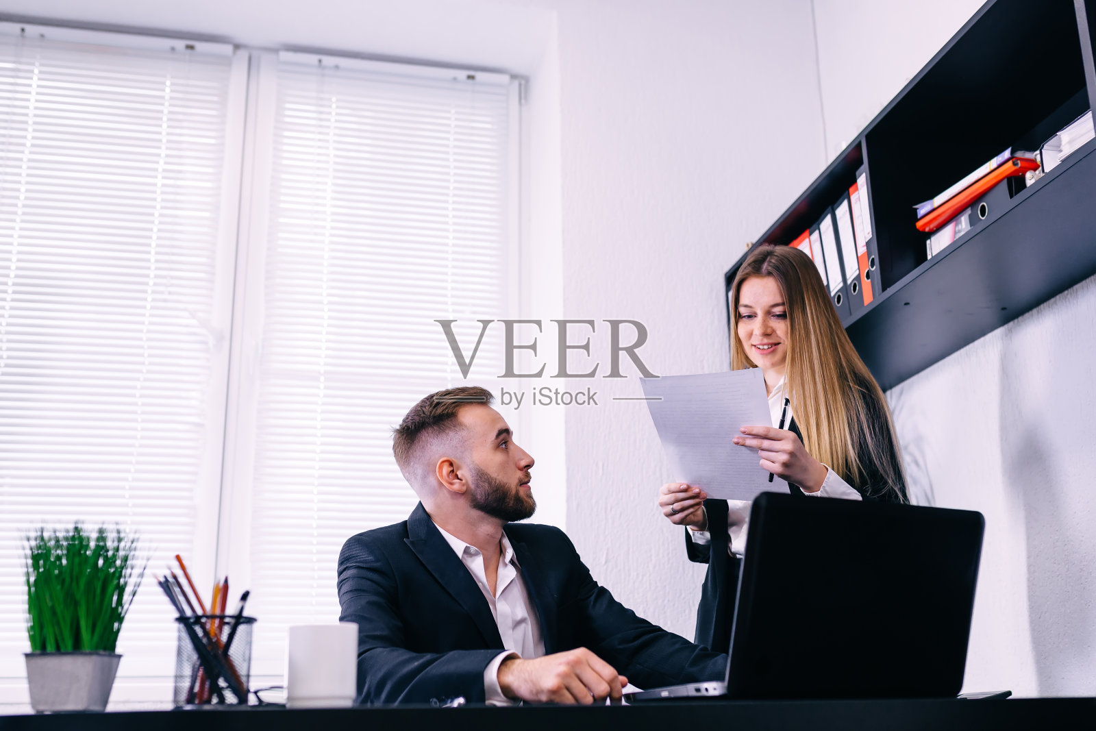 年轻人在办公室讨论文件。照片摄影图片