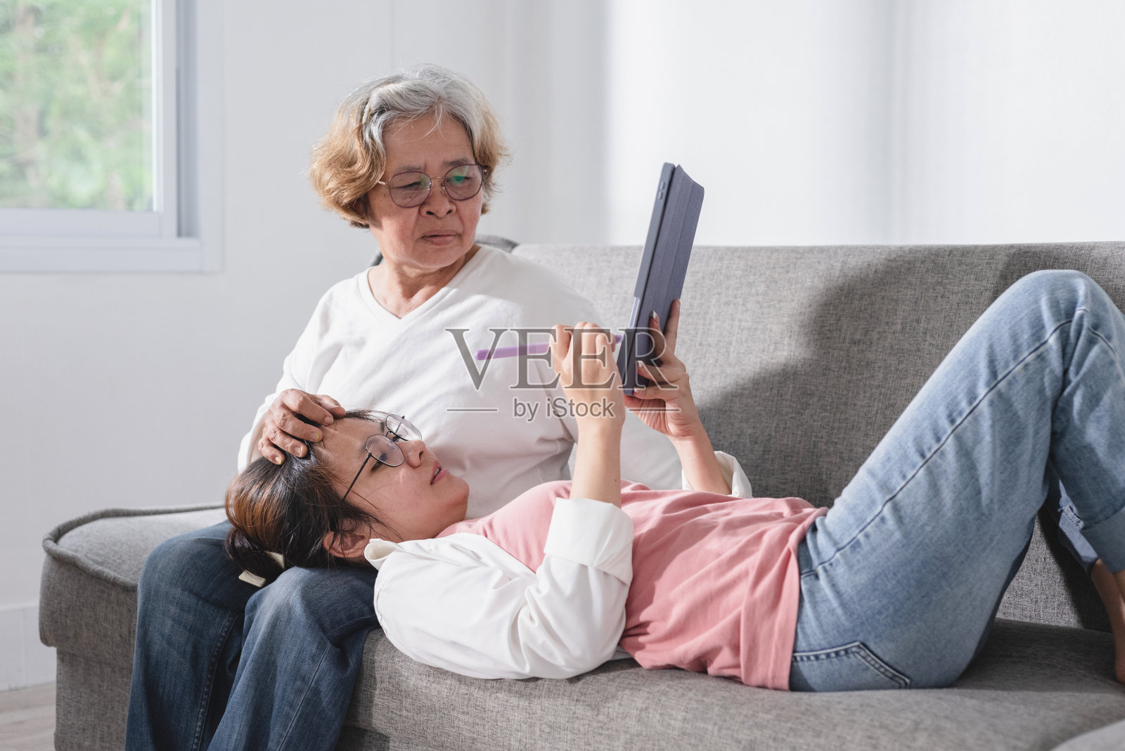 概念休闲和休闲活动，亚洲青少年和老年妇女观看和讨论内容的平板电脑屏幕，在客厅，放松。照片摄影图片