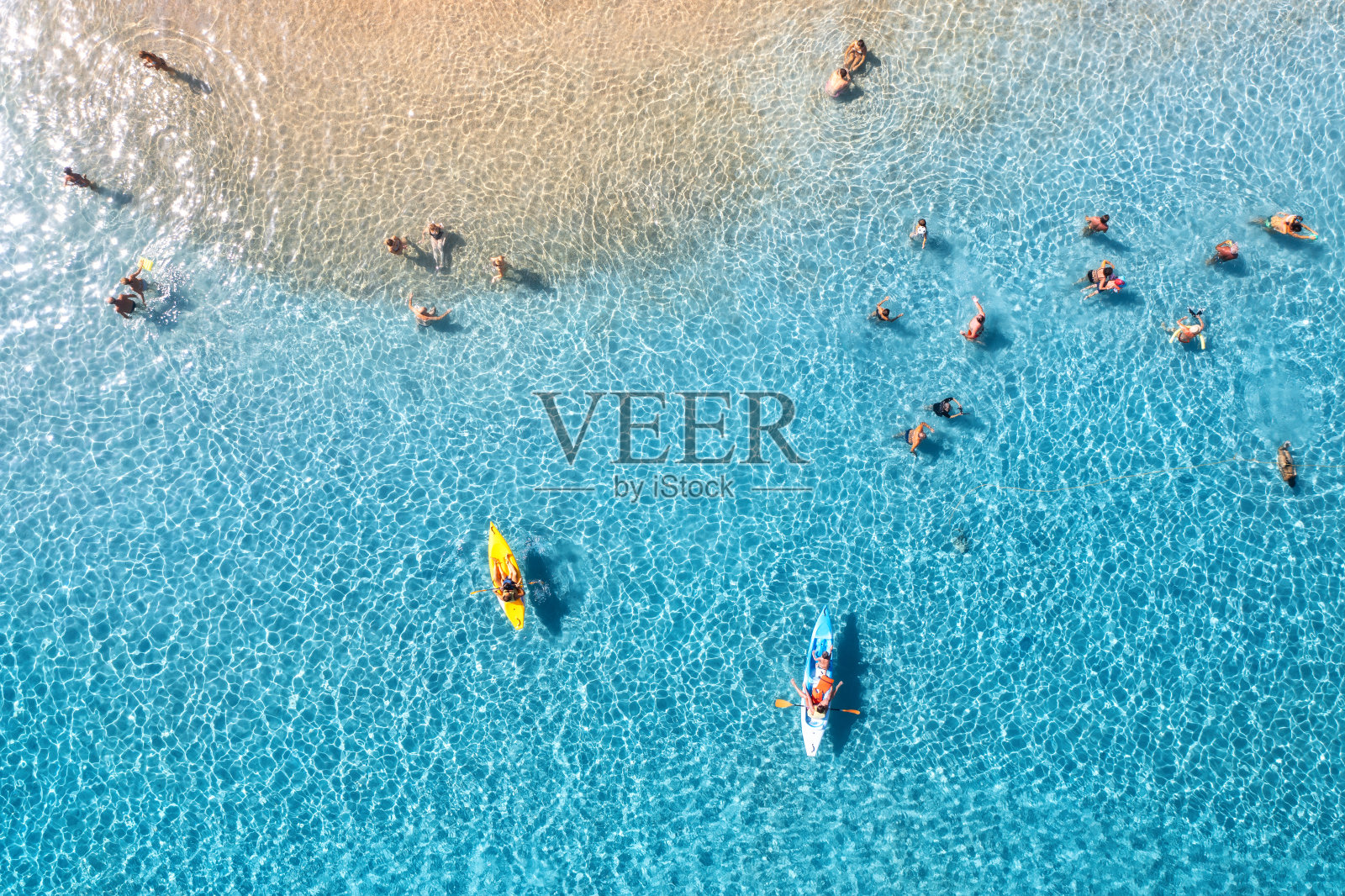 鸟瞰皮划艇，人们在蓝色的大海和日落时的沙滩上游泳。意大利撒丁岛的夏天。从无人机俯视独木舟，海岸，透明的水。色彩斑斓的热带景观。旅行照片摄影图片