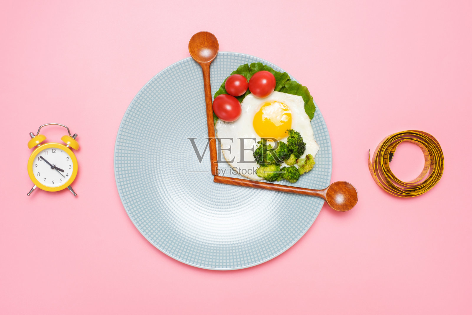 盘子与健康的食物，木制勺子和卷尺在粉红色的背景上俯瞰，间歇性禁食的概念。照片摄影图片