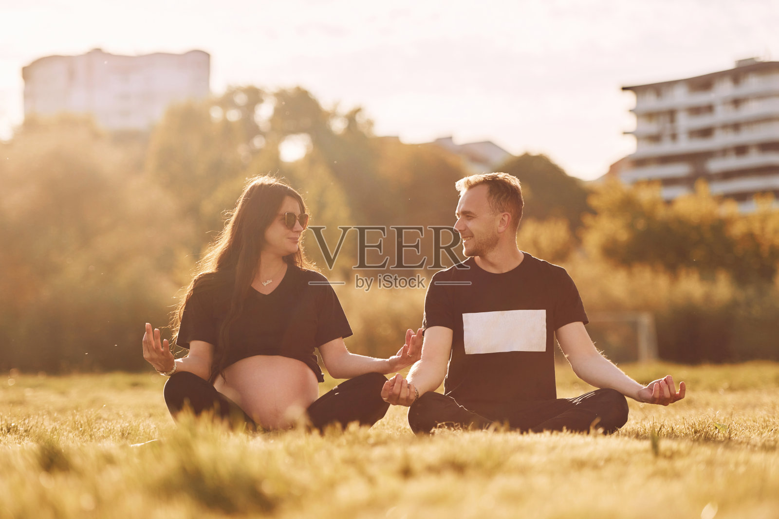 做瑜伽。女人怀孕了。一对可爱的情侣一起坐在球场上照片摄影图片