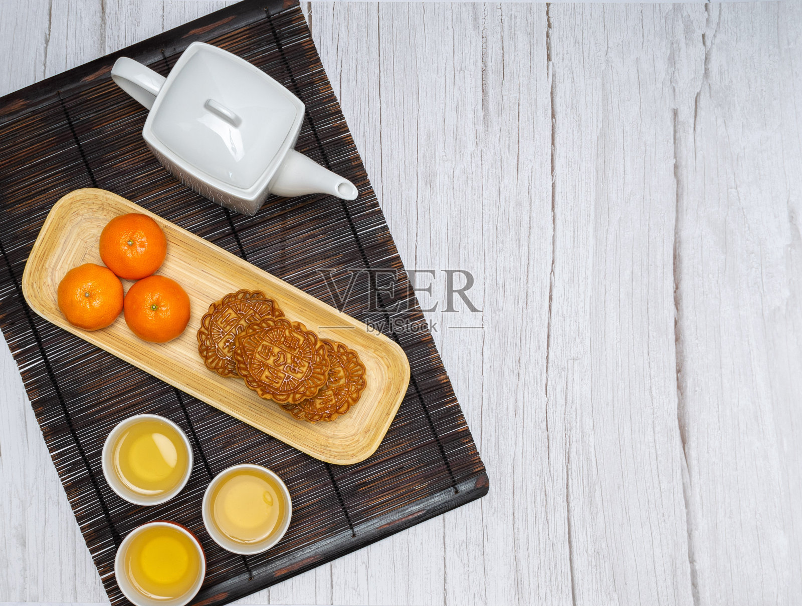 3个月饼和3个橘子放在一个竹托盘上照片摄影图片