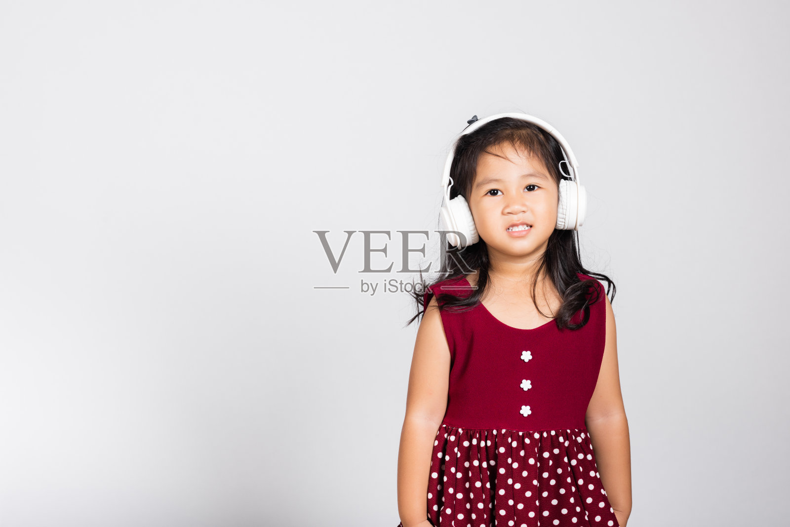 3-4岁的可爱小女孩戴着无线耳机在录音棚里听音乐照片摄影图片