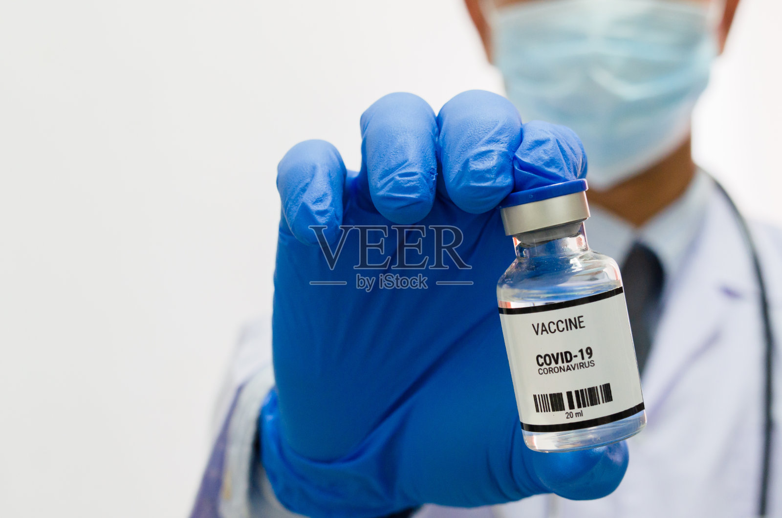 男医生戴着统一的医疗手套，手持白色背景的covid - 19疫苗病毒瓶。副本的空间。照片摄影图片