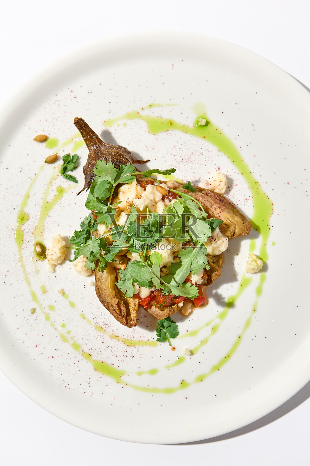 烤茄子配奶酪放在白色的桌子上，有刺眼的阴影。唯美的意大利食物——白色盘子上的烤茄子。简约风格的酿茄子。素食菜单中的填馅茄子。照片摄影图片