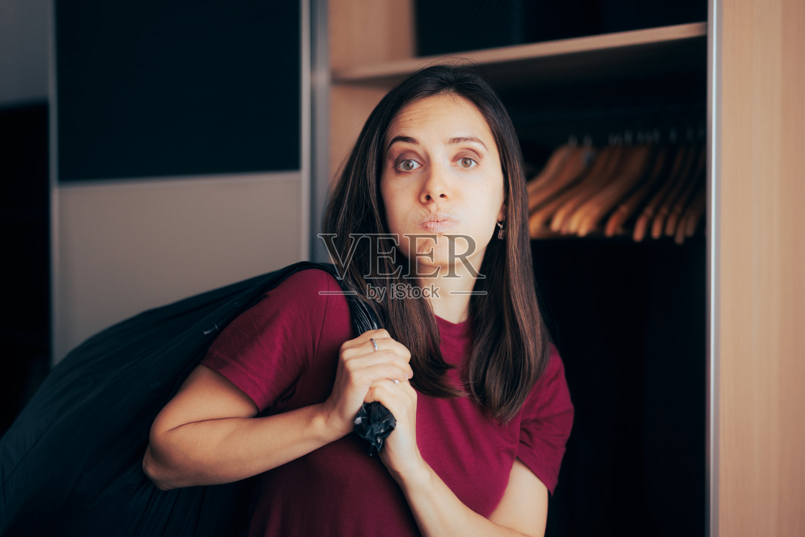 有压力的女人清理她的衣橱，扔掉衣服照片摄影图片