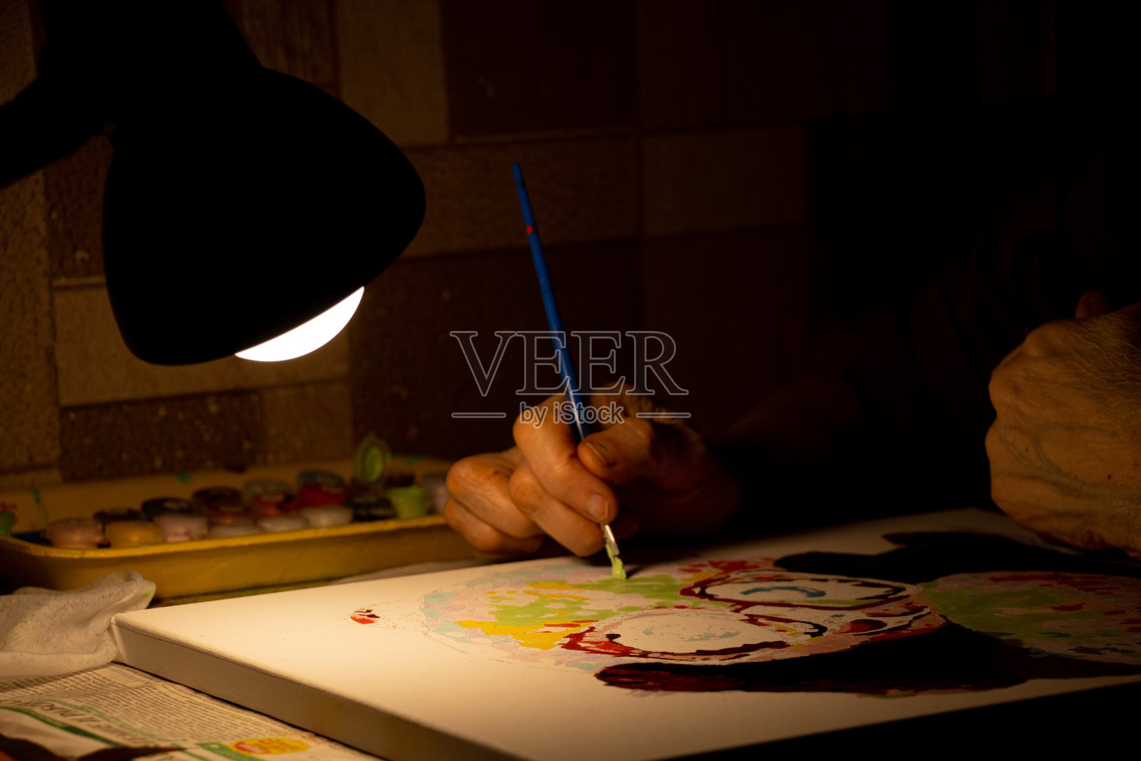 老妇人在黑暗中用油彩在画布上画一幅画，在家里画一幅画，艺术和爱好，奶奶的照片摄影图片