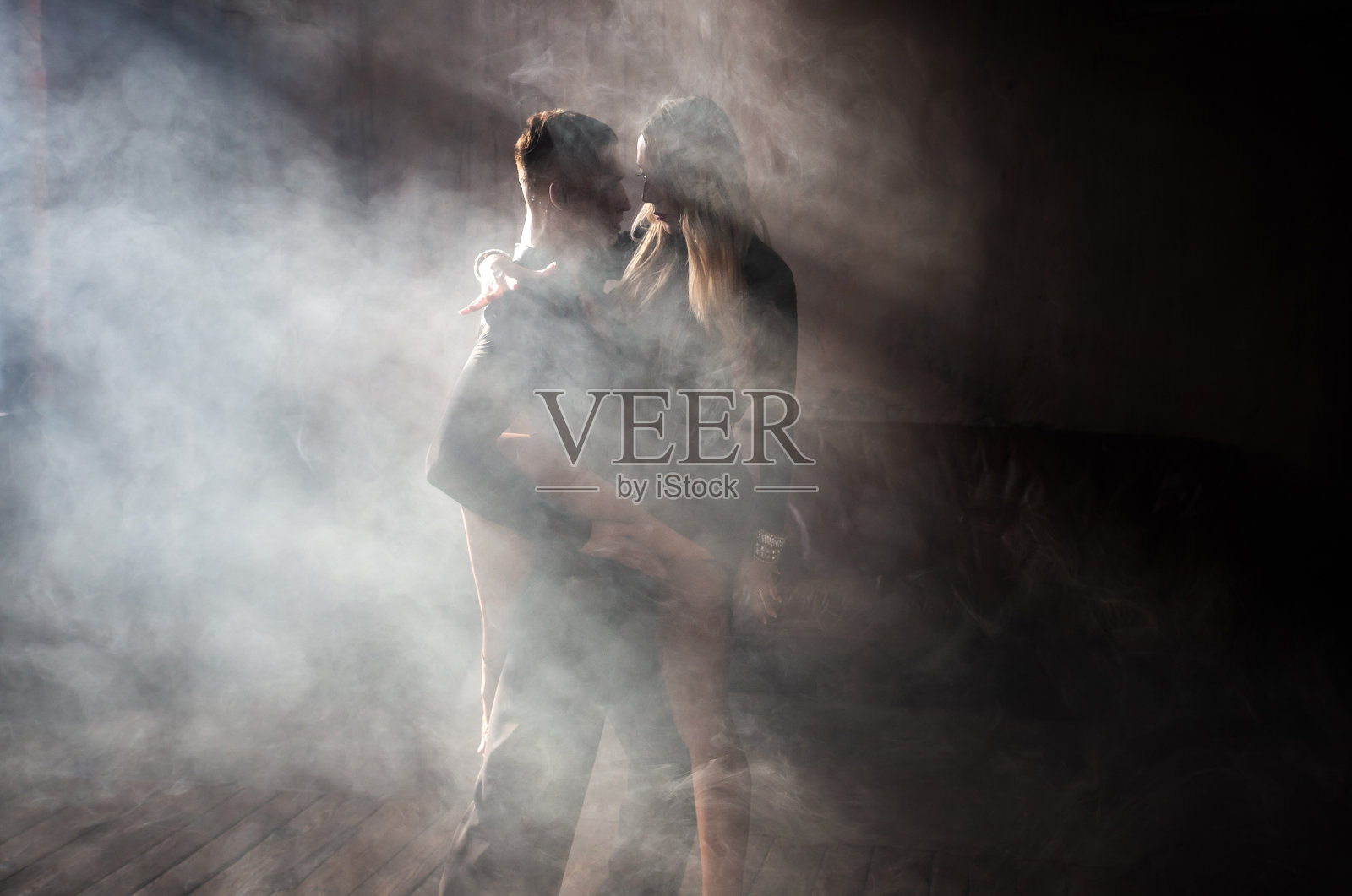 一对专注的专业交谊舞舞者正在阁楼工作室跳舞。美丽的艺术表现与沉重的烟雾。运动生活的概念。激情与情感的舞蹈。照片摄影图片