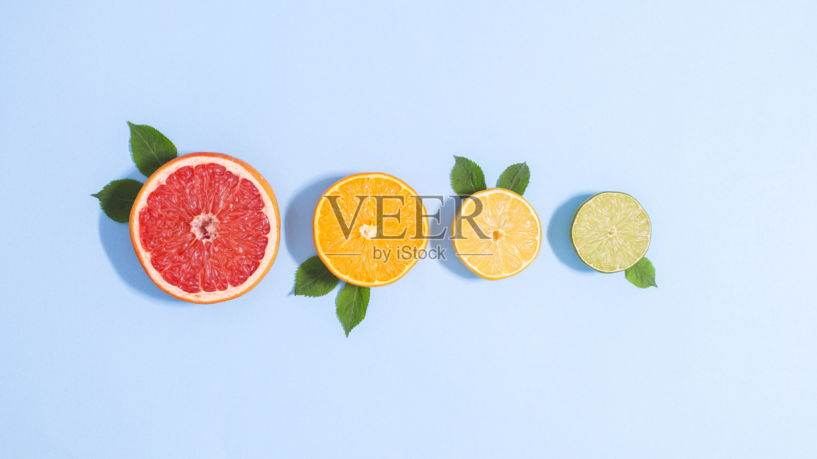 创造性的蓝色背景与切片柑橘与绿叶。平铺夏季热带概念照片摄影图片