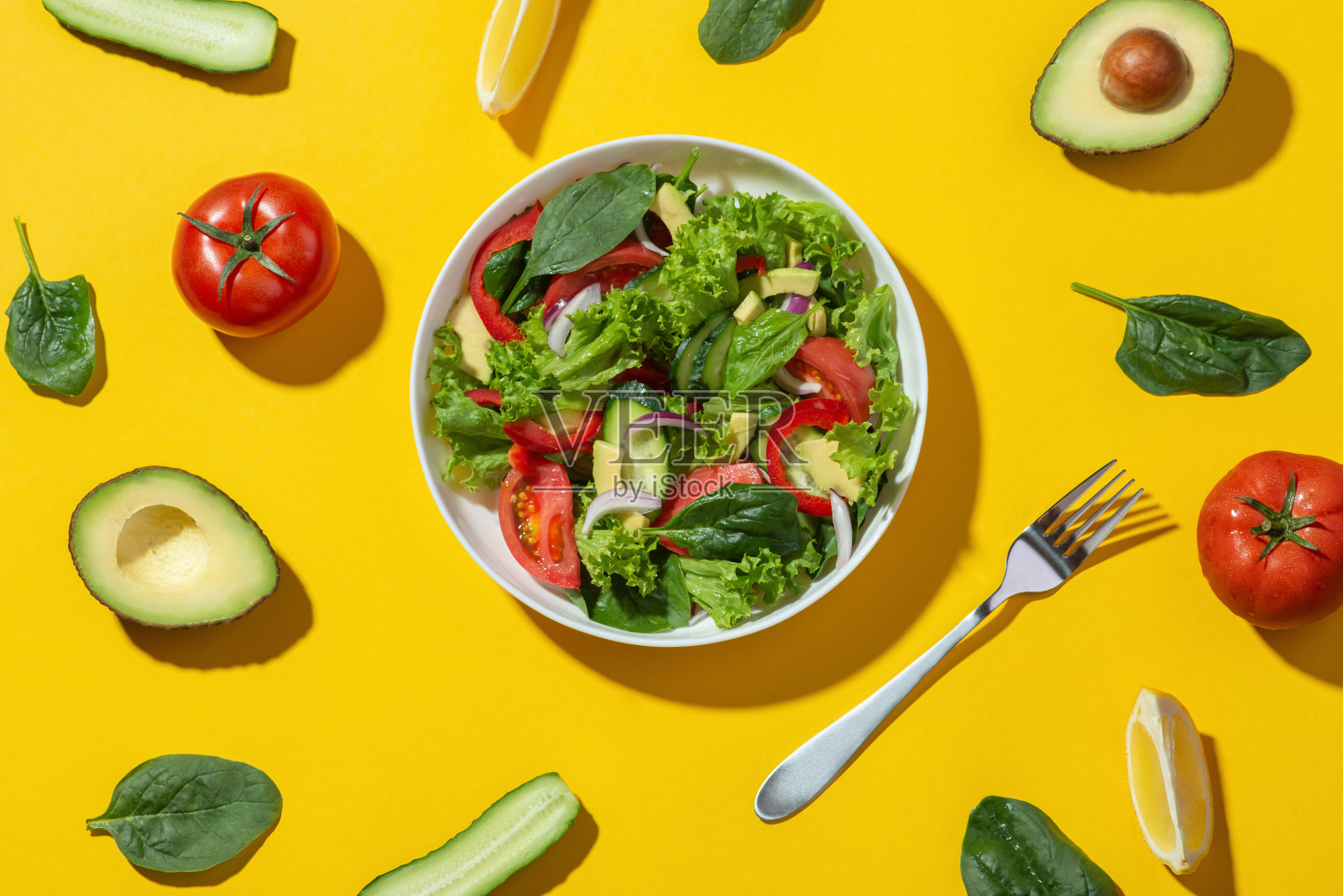 牛油果蔬菜沙拉，白色盘子，黄色背景。烹饪。饮食。照片摄影图片