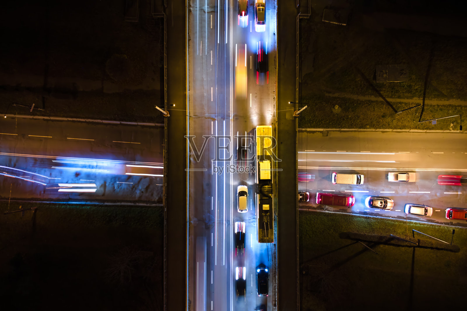 夜间快速移动的繁忙交通的十字路口鸟瞰图。城市交通的俯视图。运动模糊了车辙灯的尖峰时刻照片摄影图片