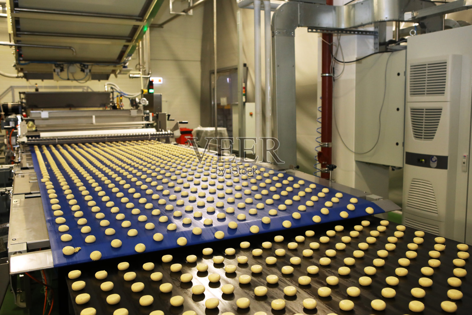 在糖果工厂控制生产香料蛋糕的大型传送带机器的工作。饼干生产线。创新的饼干的生产。照片摄影图片