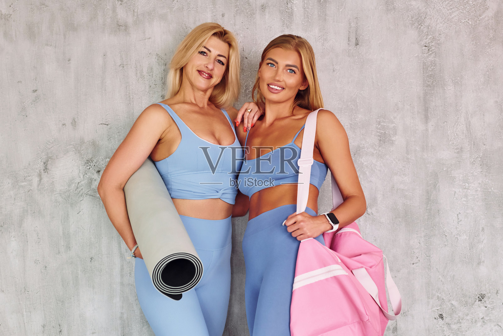 手拿包和瑜伽垫。穿着运动服装的漂亮女人在室内的工作室照片摄影图片