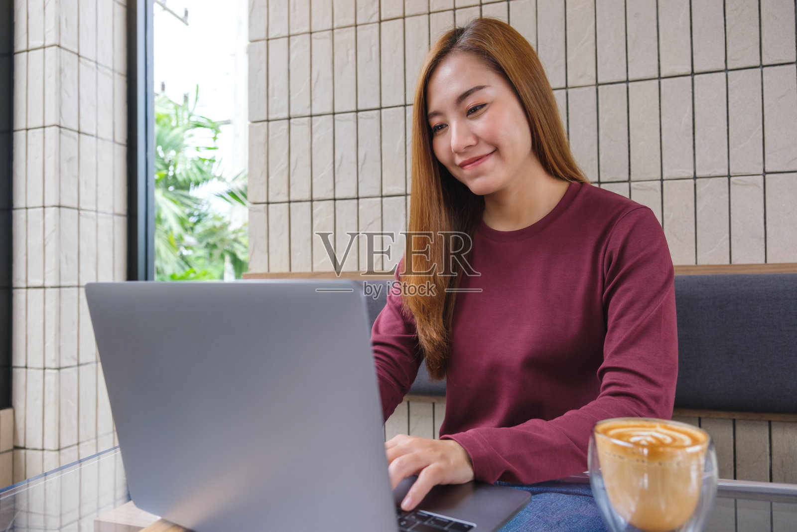 肖像形象的年轻女子使用和工作的笔记本电脑与咖啡杯在桌子上照片摄影图片