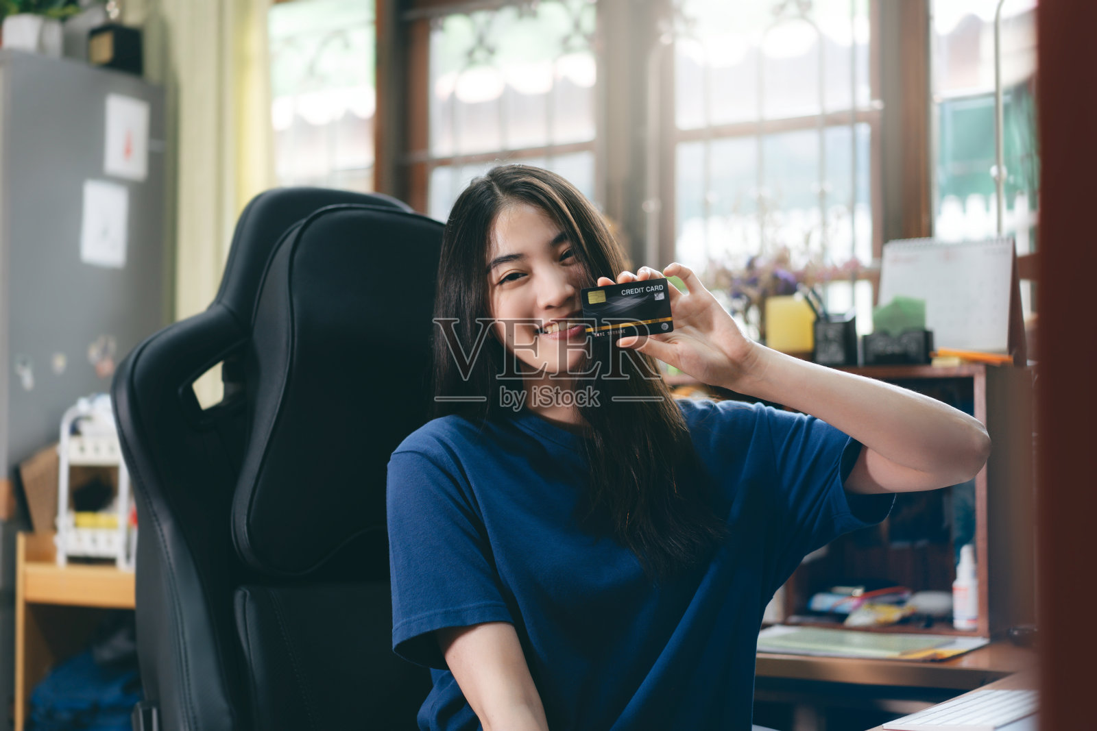 年轻的成年亚洲女性持有信用卡在家里进行网上支付。照片摄影图片