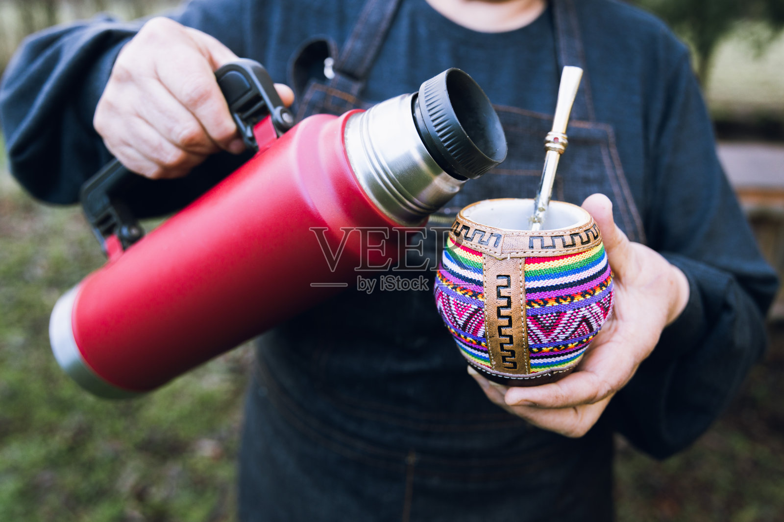 无法辨认的女人服务伴侣与一个红色的thermo，在五颜六色的民族伴侣。照片摄影图片