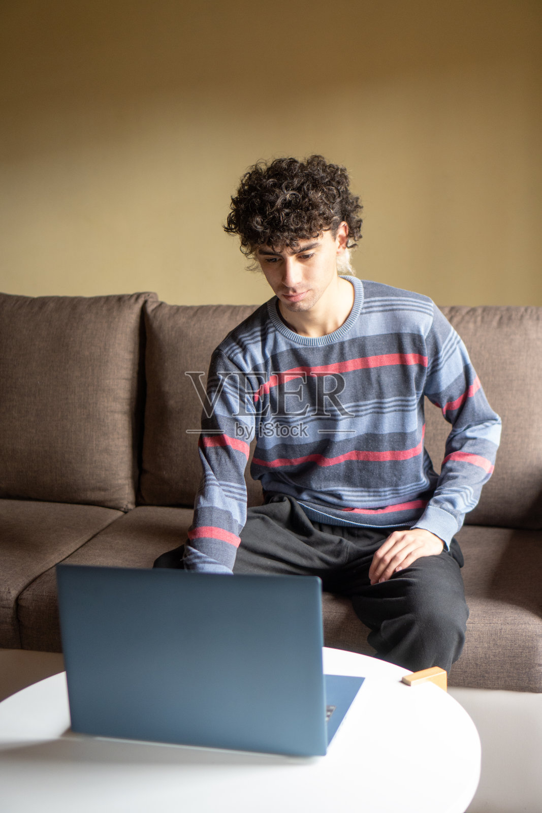 留着卷发的年轻人在用笔记本电脑照片摄影图片