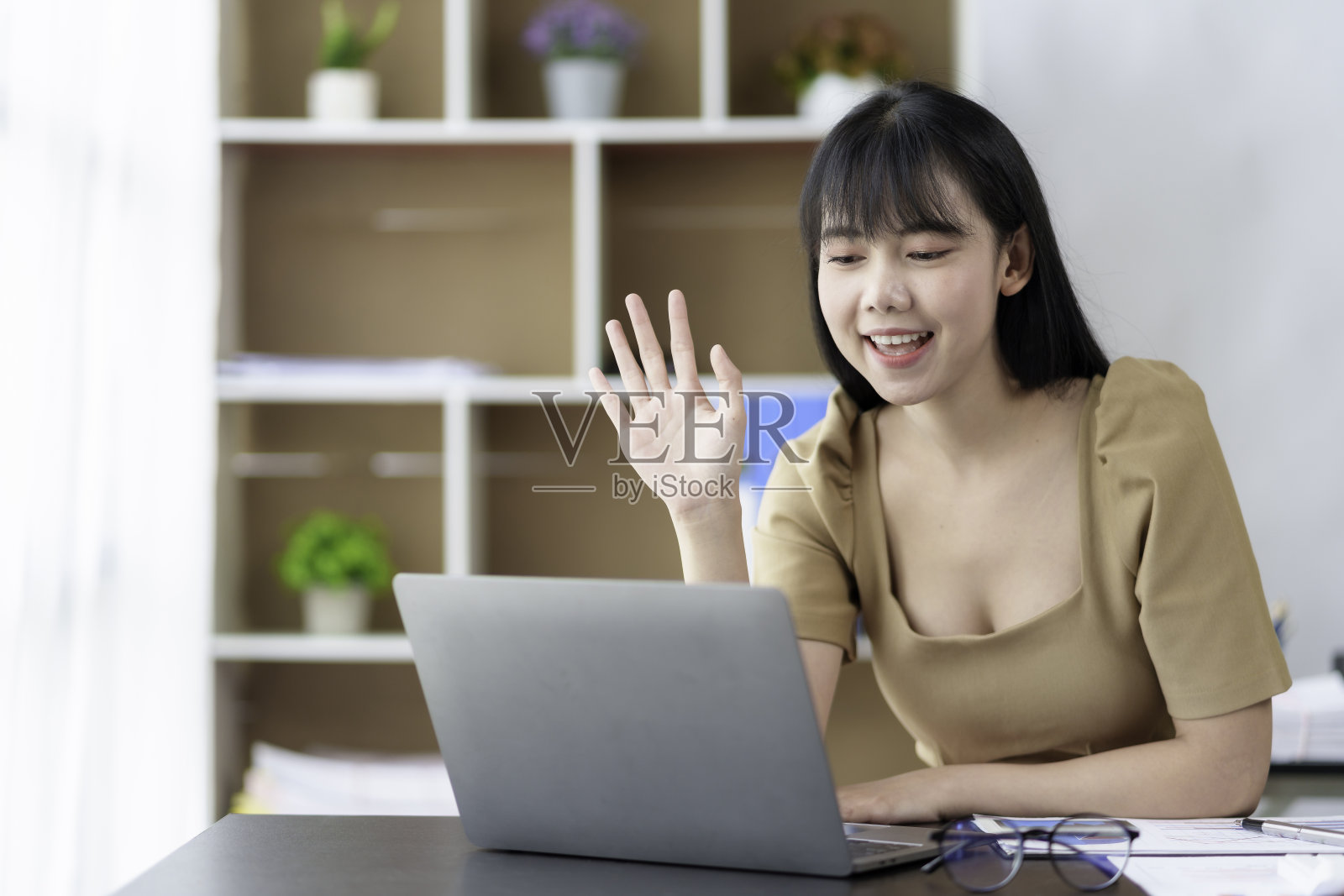 年轻的亚洲女商人在办公室通过笔记本电脑进行视频通话。照片摄影图片