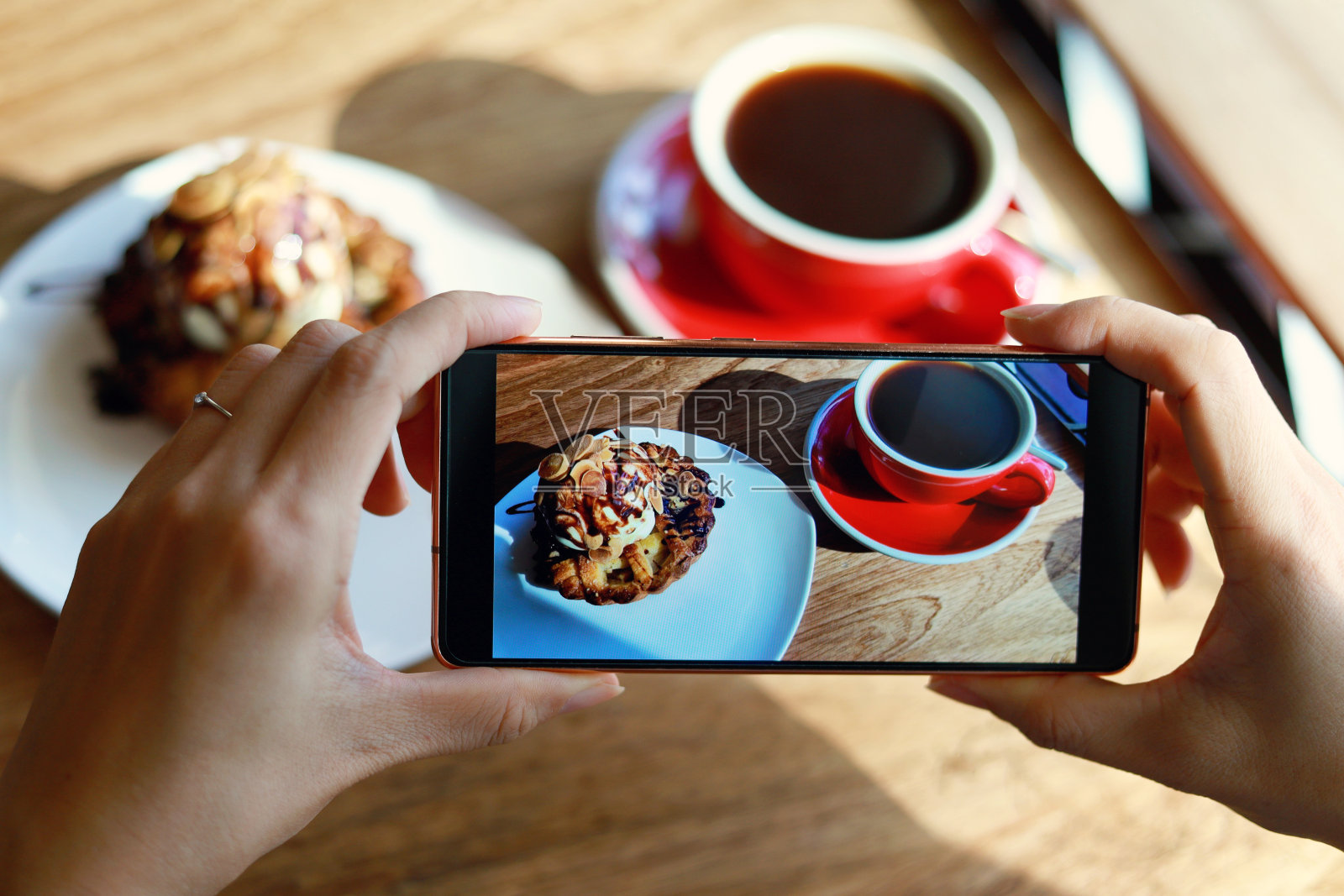 一名女子正在用智能手机拍摄她的甜点，外出就餐的生活方式。相机吞噬了第一文化。照片摄影图片