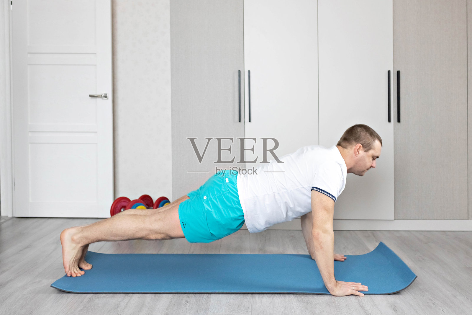 一个强壮、健康、肌肉发达的男人，在家训练平板支撑姿势。在家健身。照片摄影图片