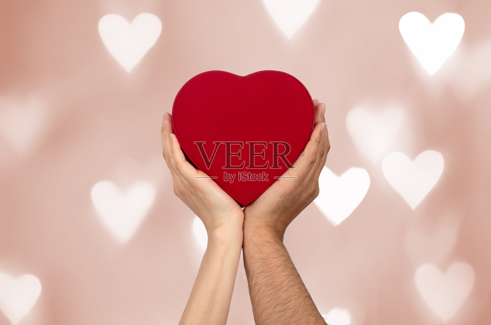 情侣手持心形礼盒与散景背景。照片摄影图片