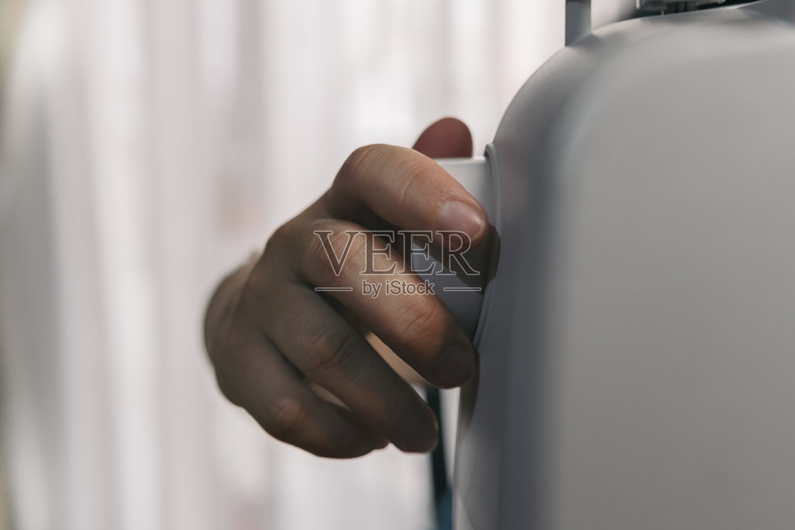 特写镜头，一个女人的手操作她的自动缝纫机的纺车。缝纫和剪裁工作在家里。照片摄影图片