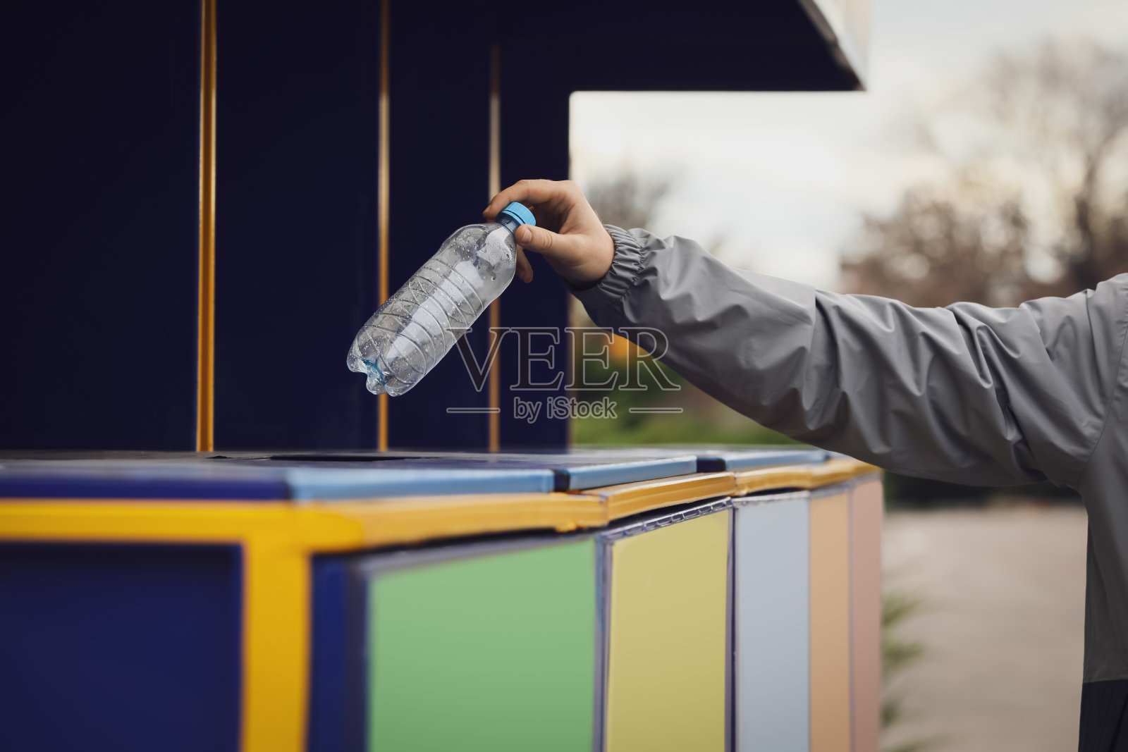 一名男子在户外将塑料瓶扔进垃圾桶，特写。垃圾分类照片摄影图片
