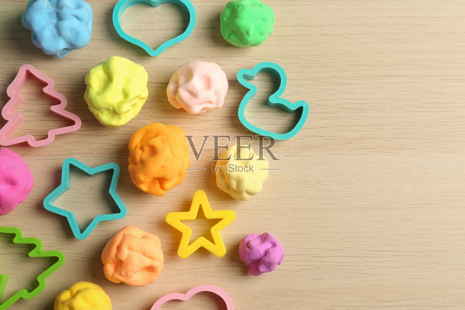 不同颜色的橡皮泥用模具打在木桌上，平铺。空间的文本照片摄影图片