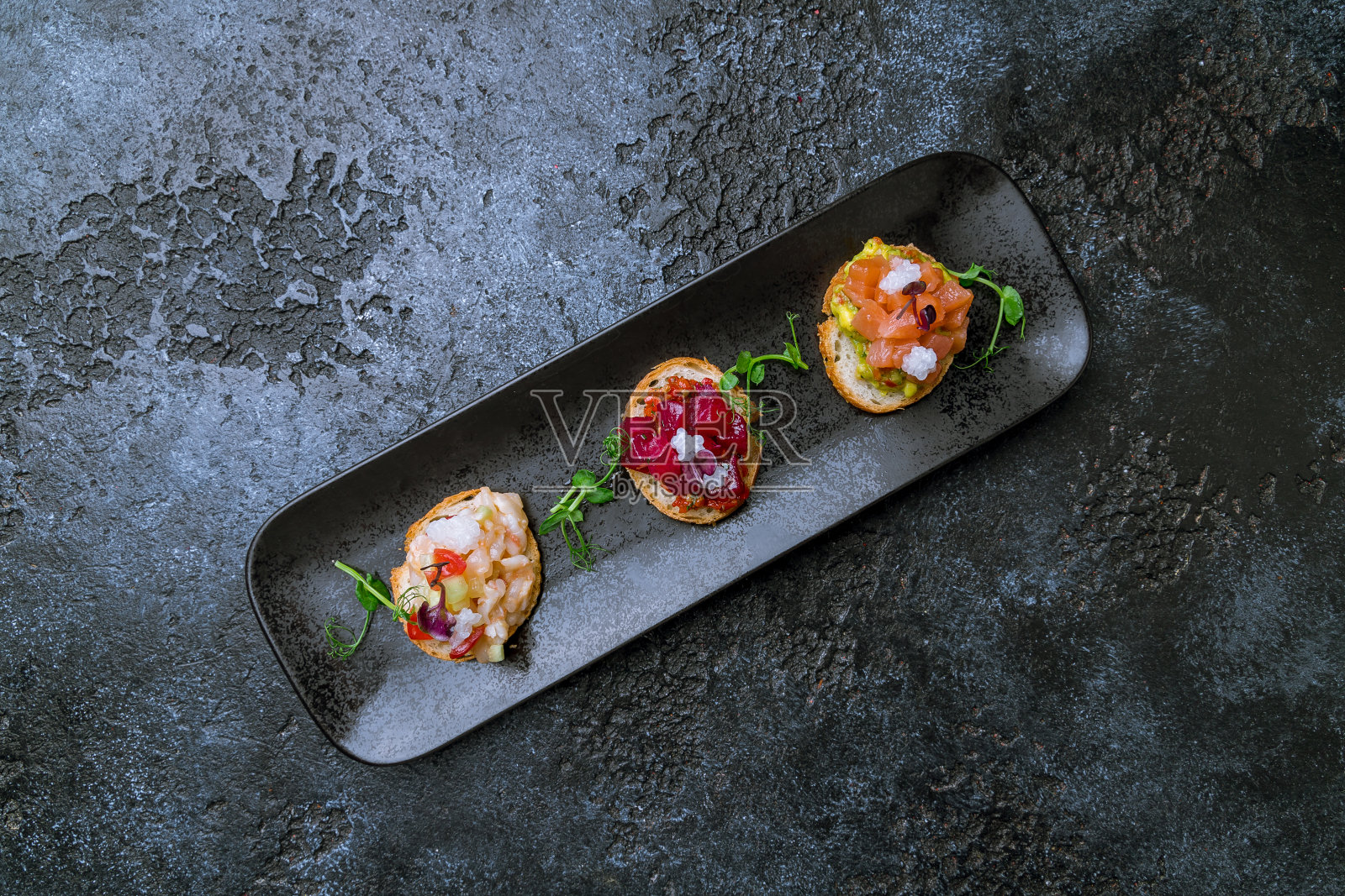 什锦面包放在黑色盘子上，在深色的石头桌上俯瞰照片摄影图片