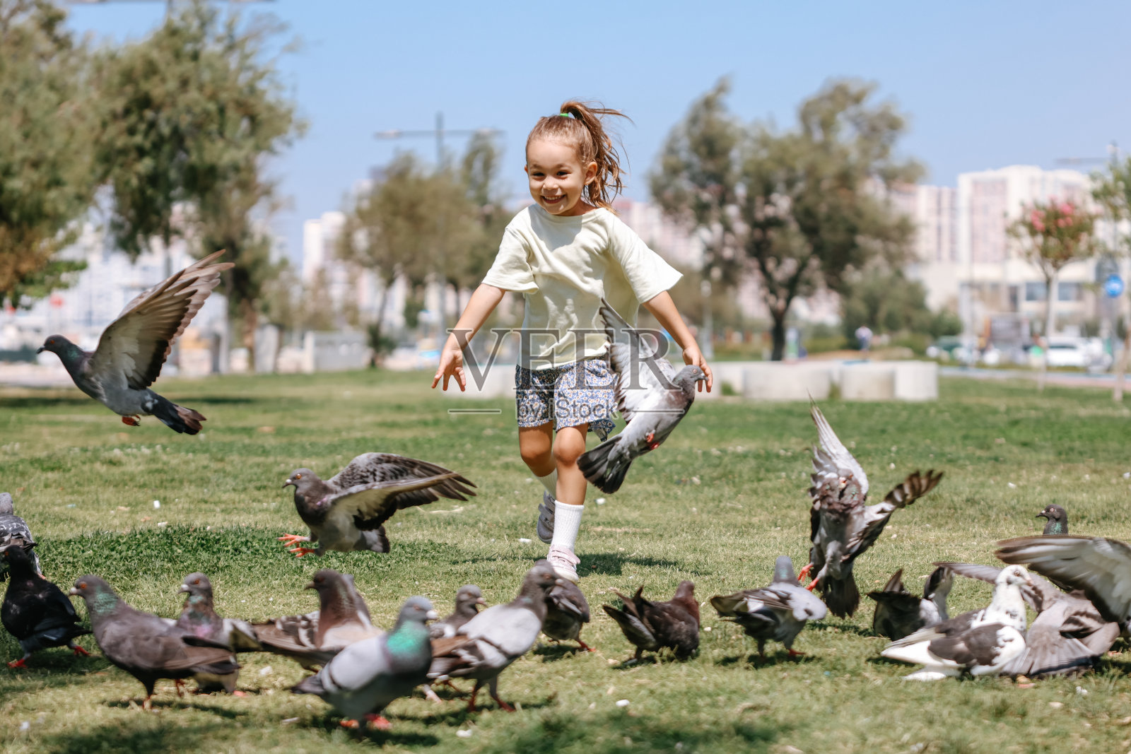 小女孩跑向公园里的一群鸽子照片摄影图片