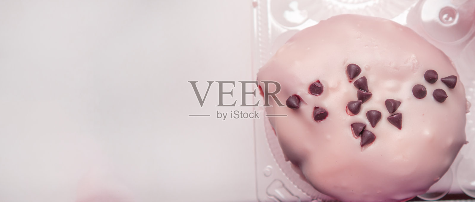 美味的甜甜圈用糖霜和巧克力片俯视，横幅上有一个复制的空间在左边，粉红色着色照片摄影图片