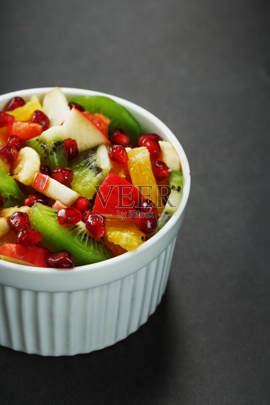 水果沙拉在一个白色的杯子在黑色的背景，自由空间的文字。照片摄影图片