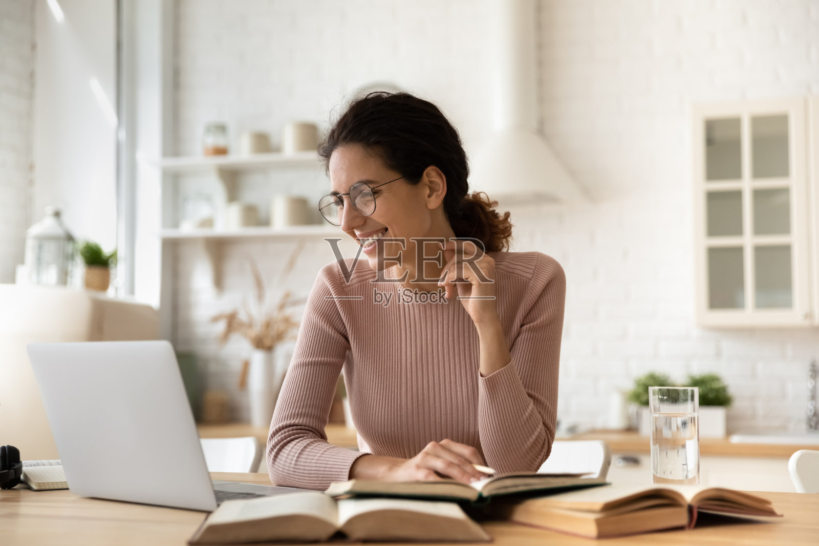 女性电子学习用电脑堆在桌子上的教科书照片摄影图片