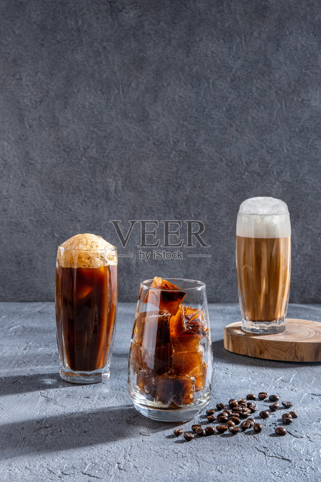 冰咖啡在一个高脚杯与奶油倒在和咖啡豆。冷咖啡饮料在黑暗的背景与复制空间。在黑暗的桌子上放置不同种类的咖啡饮料。照片摄影图片