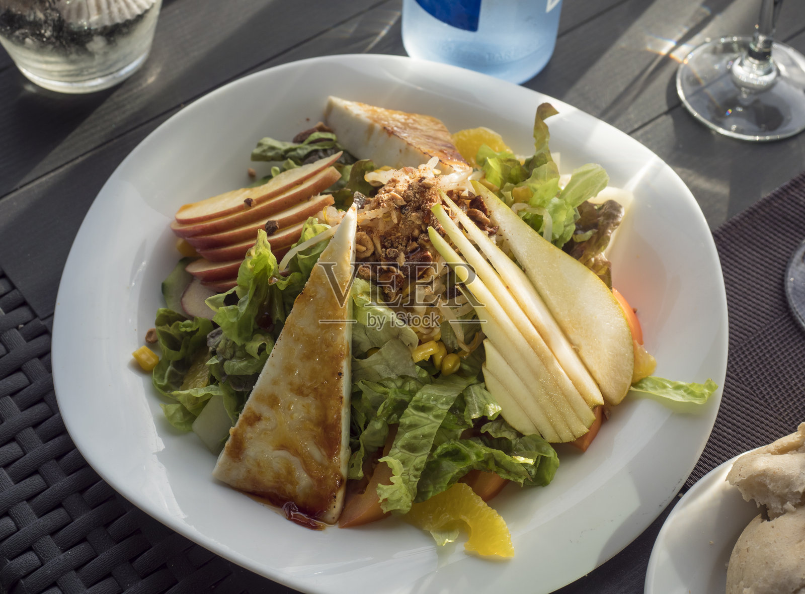 la Palma海鲜餐厅餐桌上的白色盘子，新鲜蔬菜沙拉，自制山羊奶酪，生菜，梨和焦糖坚果。有选择性的重点。照片摄影图片