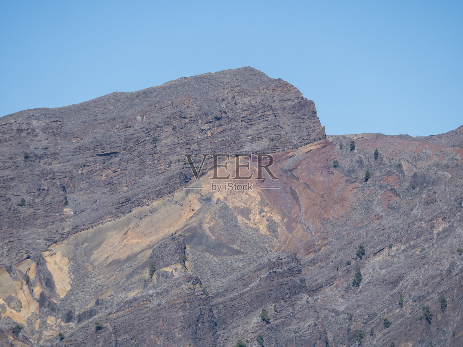 在西班牙加那利群岛的拉帕尔马岛上，与山峰Roque de los Muchachos一起观察火山口de Taburiente五彩斑斓的火山岩。蓝色的天空背景照片摄影图片