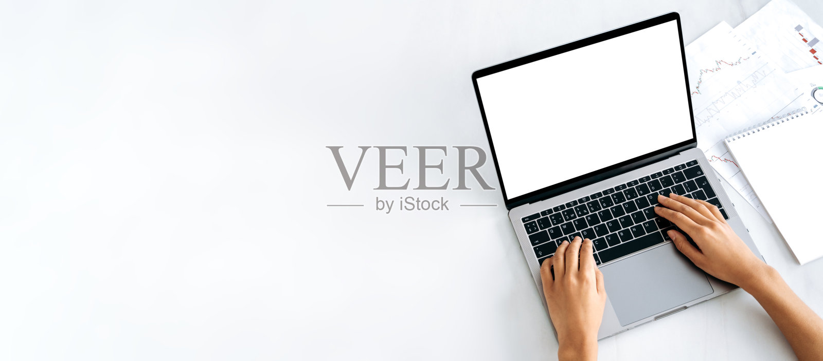 旁边放着一台白色屏幕的笔记本电脑、财务图表和记事本。女性双手放在键盘上，浏览互联网，在线通信。复制空间，模型概念照片摄影图片
