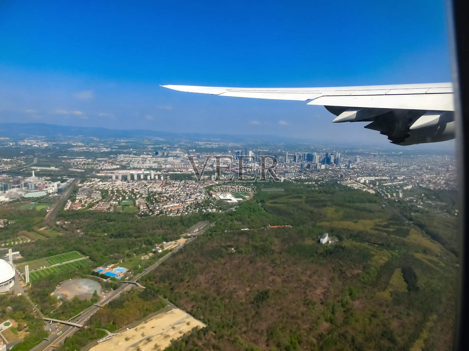 机翼、高速公路交汇处和绿色森林的飞机窗口视图。照片摄影图片