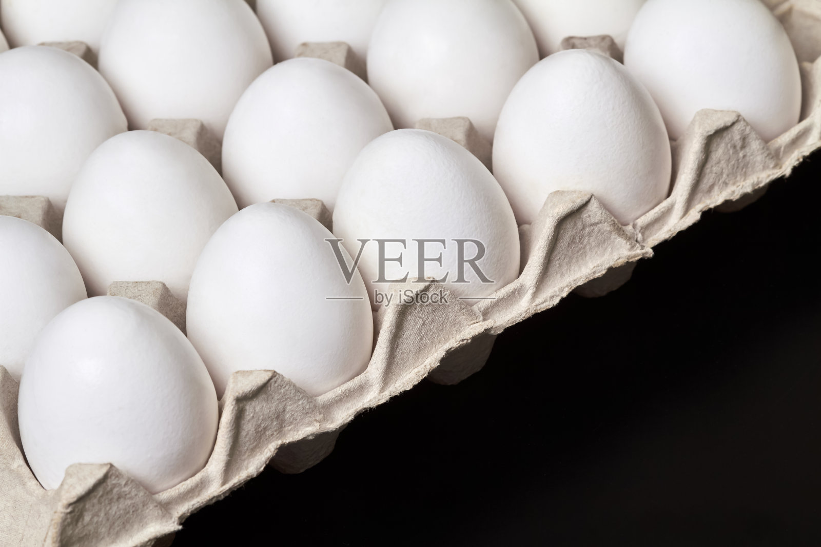 黑色背景上放着白色鸡蛋的纸板托盘照片摄影图片